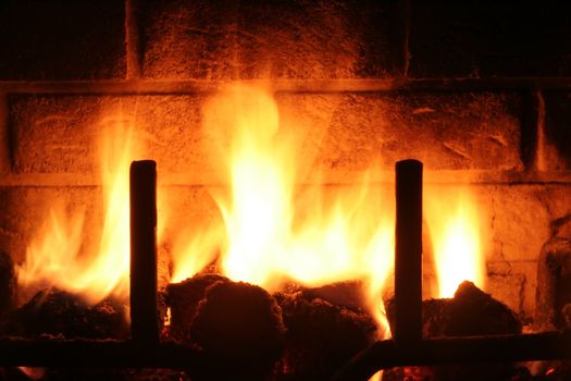 Flames light up the warm scene of a fireplace.
