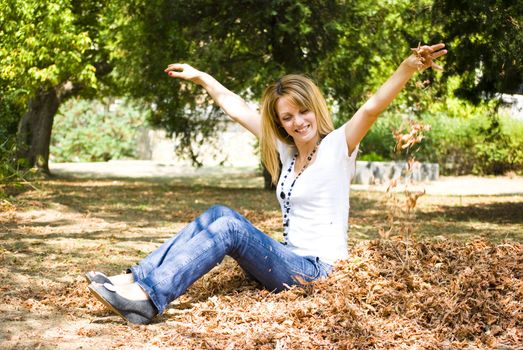 beautiful young model throwing leaves in park