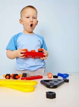 Little boy playing with plastic toys on blue background