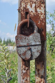 Rusty padlock on an old broken gate abandoned farmhouse