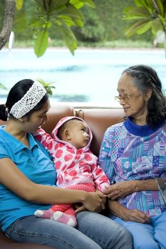 photo of three generation women: a baby, mom and grandma having a good time together