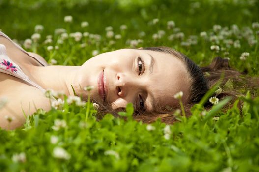 A very beautiful young woman lying down smiling in a field