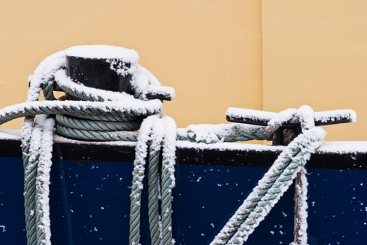 Ship ropes covered with snow in winter - color image horizontal