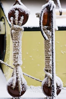 Ship ropes covered with snow in winter - color image vertical