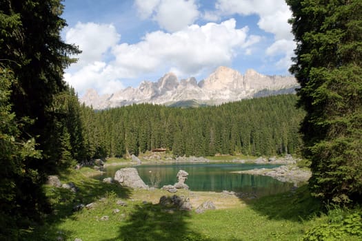 Scenic view of Carezza lake in the italian region of Trentino-Alto Adige (South Tyrol) and the Dolomites chain of the Latemar framed by trees.