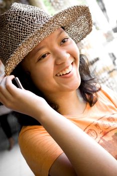 lifestyle portrait of asian female teenager smiling while having a phone call