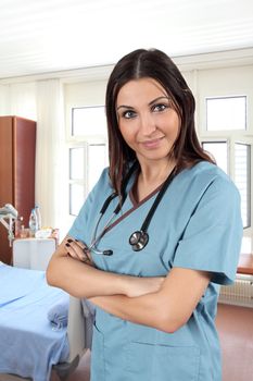 A beautiful young brunette female doctor or nurse standing in a hospital room.