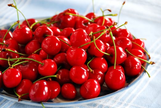 Heap of fresh appetizing red cherries on plate indoors