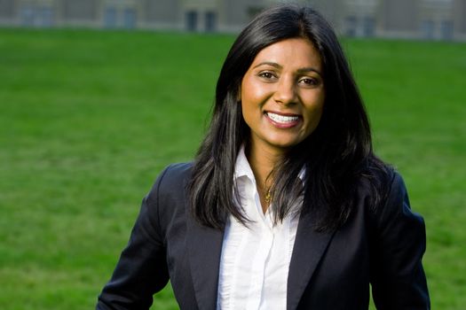 Beautiful indian girl smiling outdoors at the park with green grass