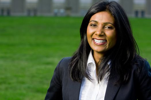 Beautiful indian girl smiling outdoors at the park with green grass