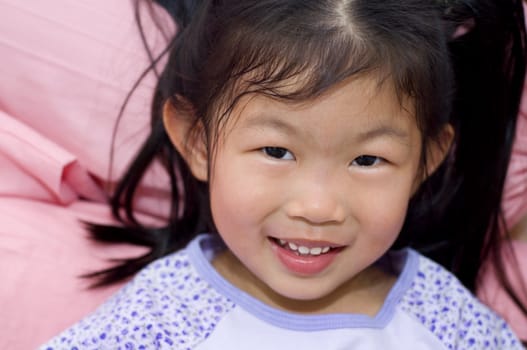 Little Asian girl lying on bed 