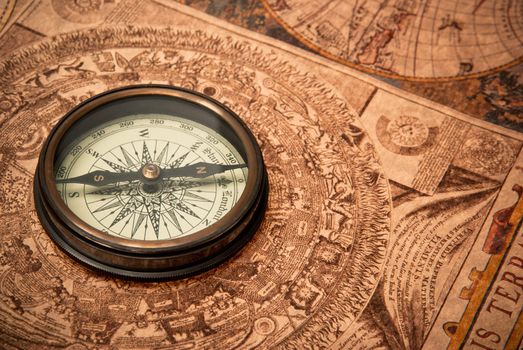 Antique compass lying on old style map. Sepia toned.