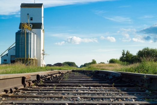 A railway going to a prairie grain elevator shot on a partly cloudy day