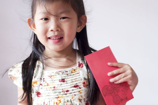 Happy chinese girl holding a chinese red envolope. Red envelope or red packet is a monetary gift which is given during holidays or special occasions, such as weddings or Lunar New Year.