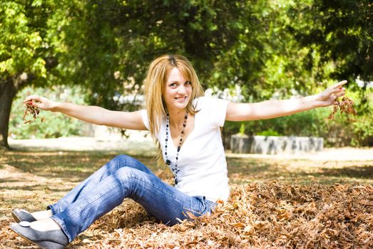 beautiful young model throwing leaves in park