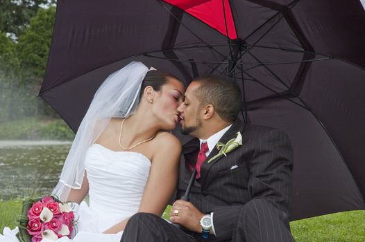 Just married multi ethnic couple kissing under an umbrella