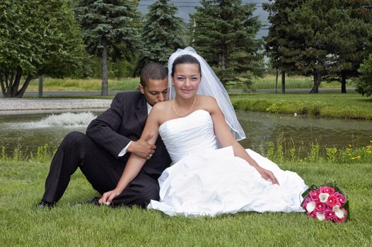 Just married multi ethnic couple sitting in the grass