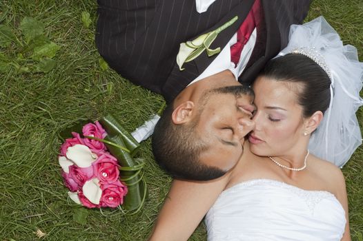 Just married multi ethnic couple laying in the grass