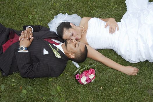 Just married multi ethnic couple laying in the grass