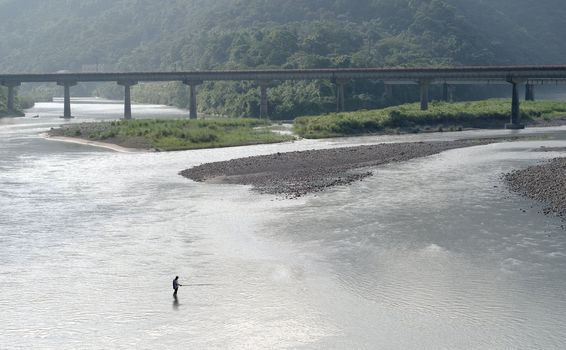 A man standed on the river and fishing.