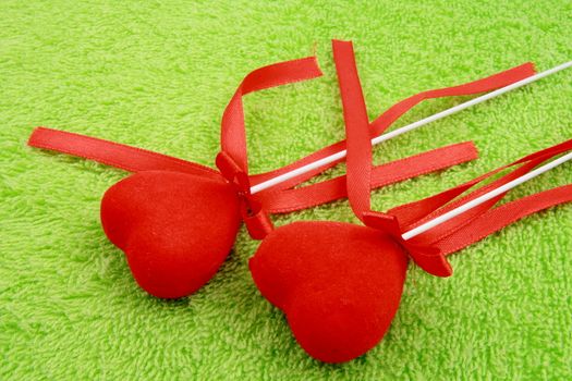two red hearts with ribbons on green fabric