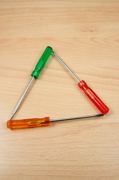 three screwdrivers on wood like a "recycle" symbol