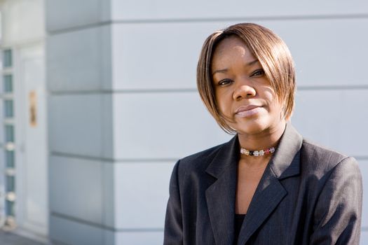 Black african american business woman posing in front of a modern office building with arms folded