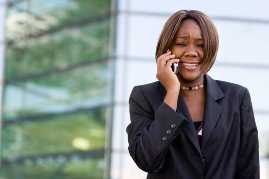 African american business woman talking on a mobile cell phone in front of an office building