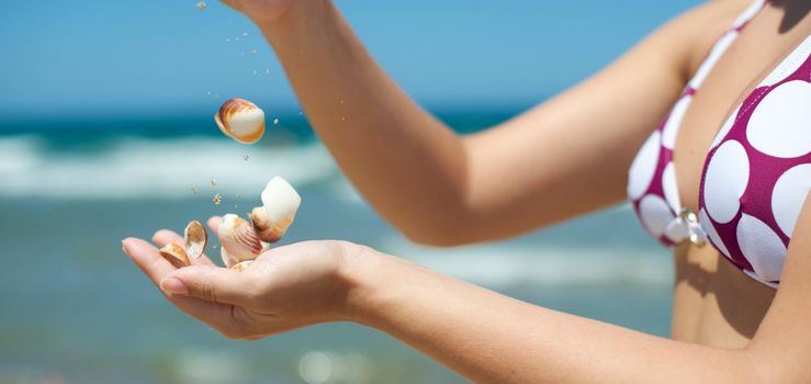 Woman playing with some shells on the beach