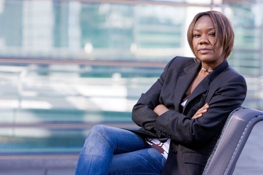 Black african american business woman posing in front of a modern office building with arms folded