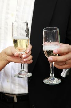 Glasses of champagne in a hand of the groom and bride