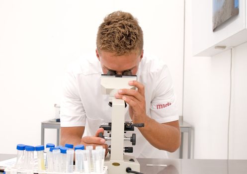 young scientist or student looking through a microscope