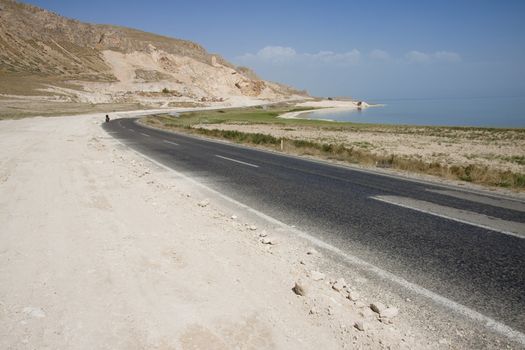Empty route on the coast - Van lake Turkey in background man on the bicycles