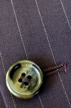 Macro of a buttonhole in a businessman's pin-stripe suit. Texture and light.