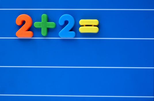 A sum, from a child's toy number set, placed on a blue, lined background. Answer left blank. Space for text elsewhere in the image.