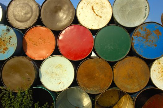 A stack of grungy old oil drums at a music festival, ready to be set out as rubbish bins.