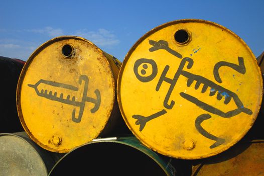 Symbols of a syringes, painted on the ends of two old oil drums that have been stacked to be used as a waste bins at a music festival.
