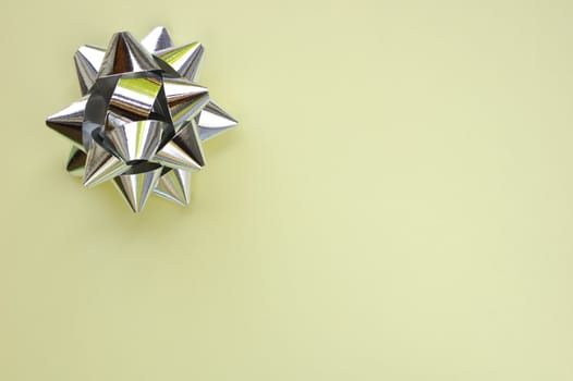 A decorative star, made from silver ribbon, on a plain cream background with space for text (copy).