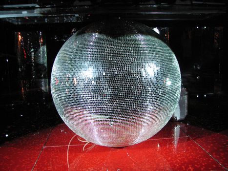 Huge mirror sphere under the board of DJ in a night club