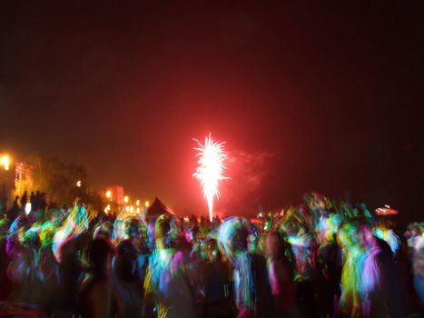 Fireworks over the crowd of people dancing on the beach