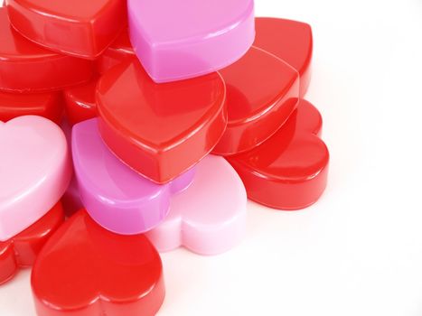 Plastic heart shapes in red, pink and lavendar, stacked up over a white background.