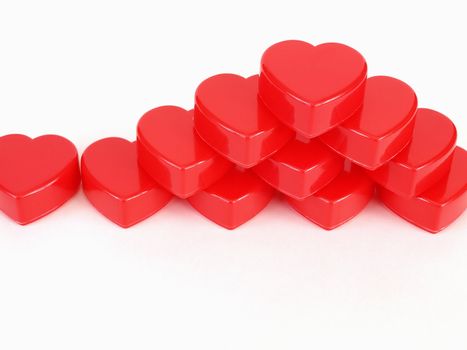 Red plastic heart shapes stacked in a pyramid formation, over white.