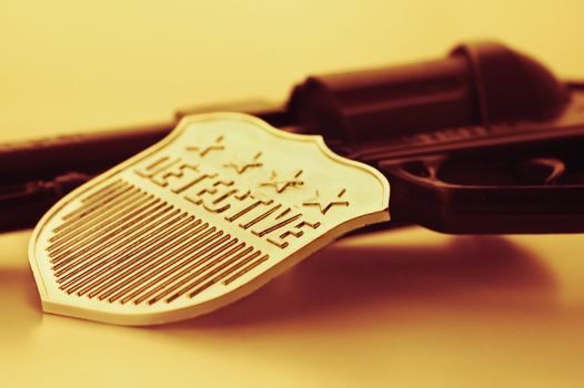 Detective badge and gun in orange light