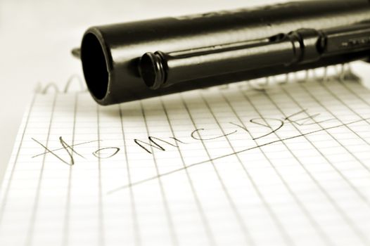 Close-up of a notepad with word 'homicide' written with pencil and gun with selctive focus