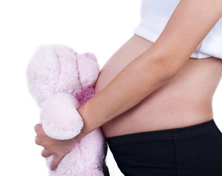 Woman holding a soft toy on her 8 months pregnant belly.