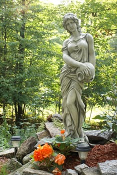 A beautiful garden statue of a woman and a vase.
