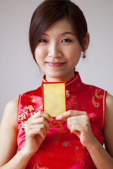 Oriental girl in cheongsam wear holding a Chinese red packet wishing you happy Chinese New Year.
