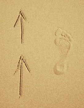 Trace of a human foot on the sand and arrows. Tourist traffic.