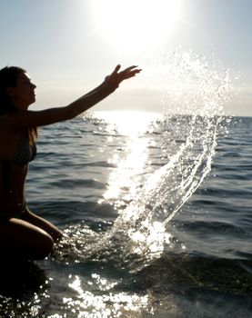 The fine young girl in sun beams laps in a sea wave     