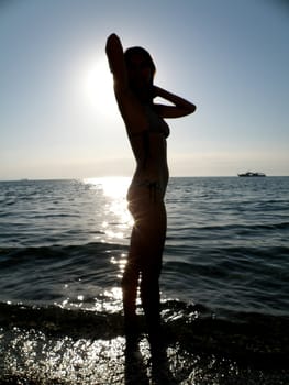 The fine young girl in sun beams laps in a sea wave